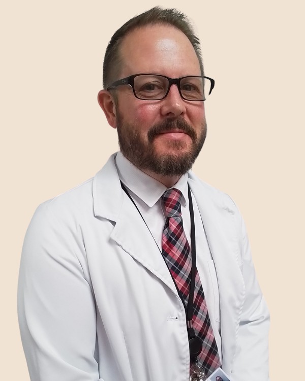 Portrait of Benjamin Clark, PMHNP-BC, wearing a white coat